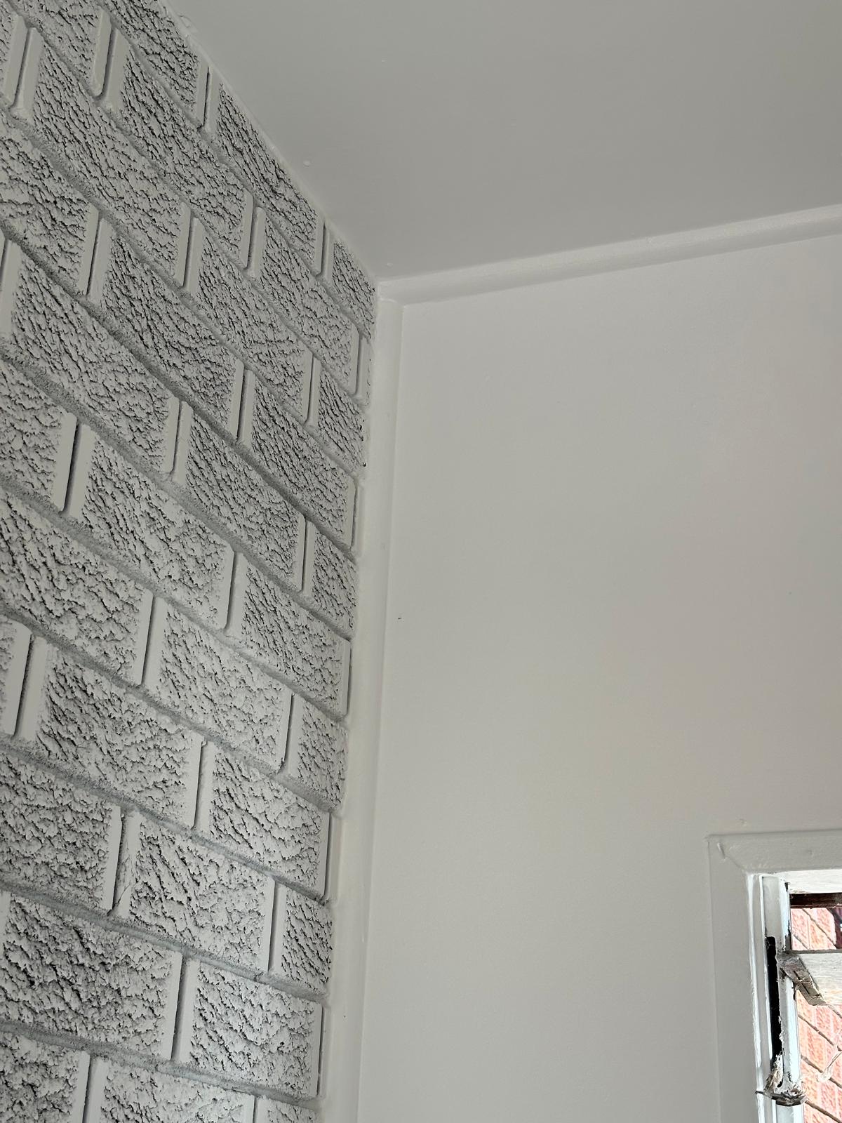 Crisp white corner finish beside a feature brick wall